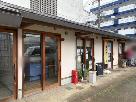 店舗棟を斜めから見た様子。手前の区画はガラス戸越しに青いカウンターが見え、奥にはのぼりと黒板が置かれた入口が続く
