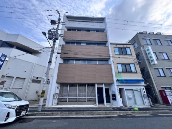 京都市上京区・西工務店ビルの正面外観。茶色の外壁と各階に並ぶ横長の窓