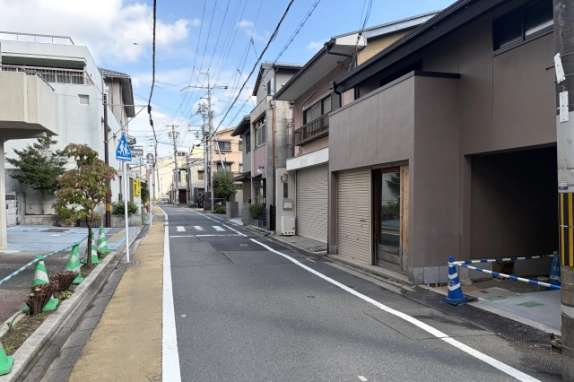 建物を右手に見た大宮通の街並み。向かい側に街路樹のある歩道と横断歩道の標識が見える