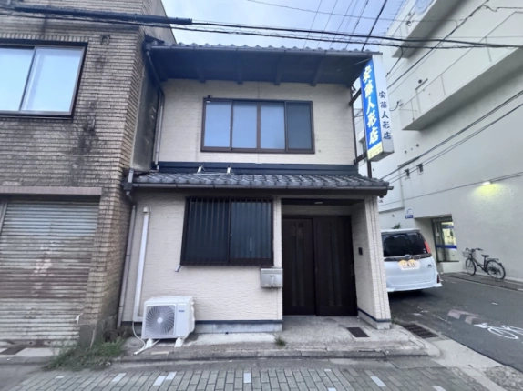 京都市上京区・米屋町京町家の正面外観。瓦のひさしと2階の横長窓、右側の玄関