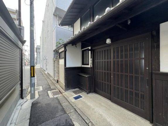 京都市下京区大黒町・七条西洞院貸家の外観。細い路地に面した木格子の引き戸と深い軒