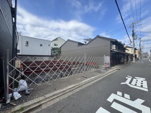 Gladvis京都室町の敷地を斜めから見た工事中の様子。左手の仮囲いと隣接する建物
