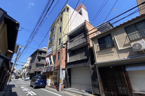 SAKURA BLD.祇園を側道から見上げた外観。建物側面と隣接する低層建物