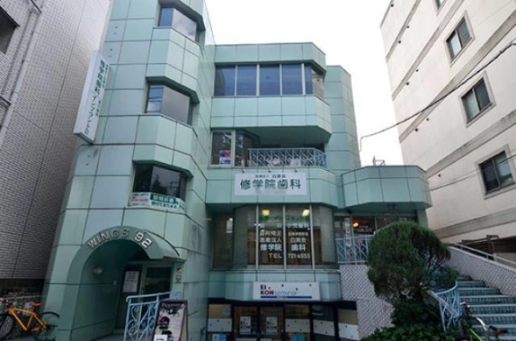 一乗寺清水町に建つウィングス92の正面外観。淡いグリーンのタイル張りの3階建てで、最上階の3階には横長の窓が並び、左にWINGS 92の文字が入ったアーチ型入口、右に外階段がある