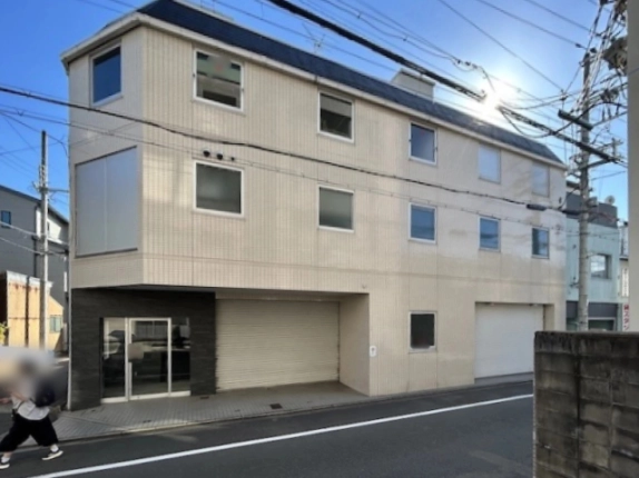 中京区瓦師町の3階建て一括貸ビルを正面から見た外観。ベージュのタイル壁に紺色の屋根、1階左に黒いタイル壁のガラス扉入口、中央と右に白いシャッター