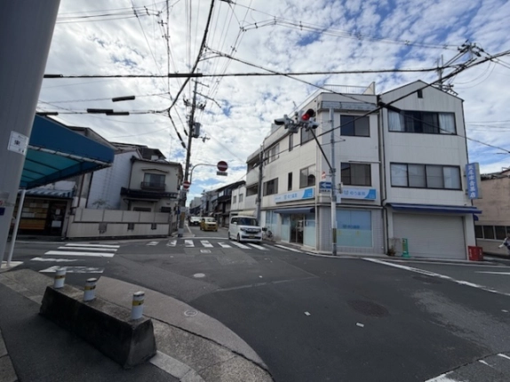 京阪清水五条駅から徒歩7分の交差点を対角側から見た街並み。右手に角地のビル、正面奥に町家の並ぶ通りが延びる