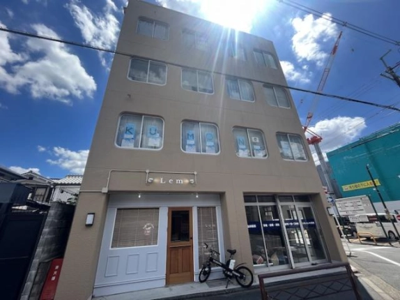 3-C号室があるビルを正面から見た外観。1階の店舗入口と上階に並ぶ横長の窓