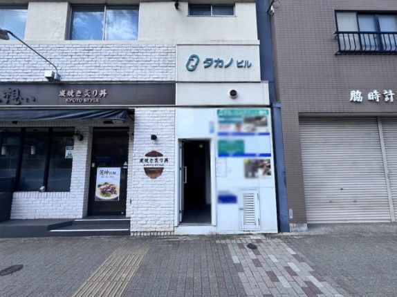 タカノビルの共用入口。建物名の表示と入口横の案内看板