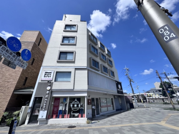 中堂寺庄ノ内町のビルを下から見上げた外観。角に縦一列で並ぶ窓