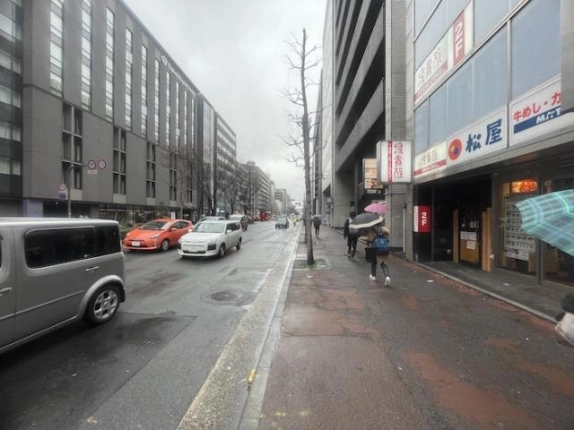 四条・烏丸駅周辺の歩道と前面道路。右手に沿道の店舗、左手に車道と向かい側の建物