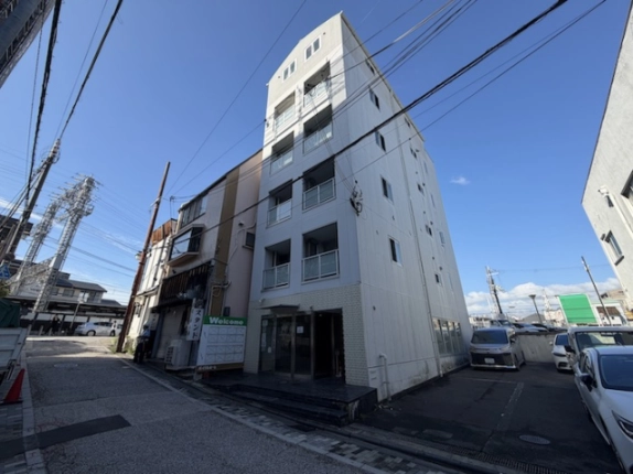 Casa La Vitaを斜めから見た全景。縦長の白い建物と側面、隣接する駐車スペース