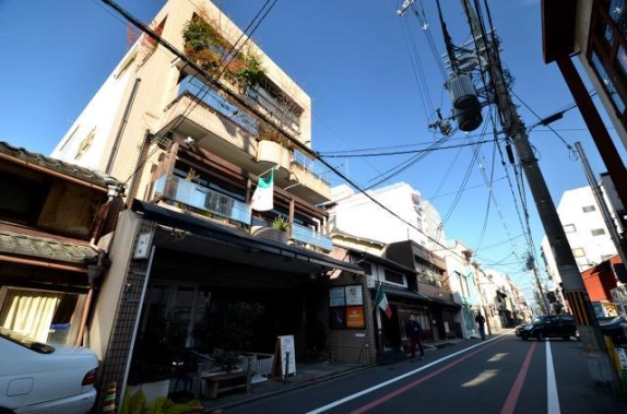 御幸町通から見上げた御幸町伽羅ビルの外観。上階のバルコニーに植栽が茂り、右手には電柱と通りが奥へ続く