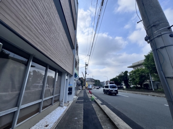 西工務店ビルのガラス面に沿う歩道。左手の外壁と右手の前面道路