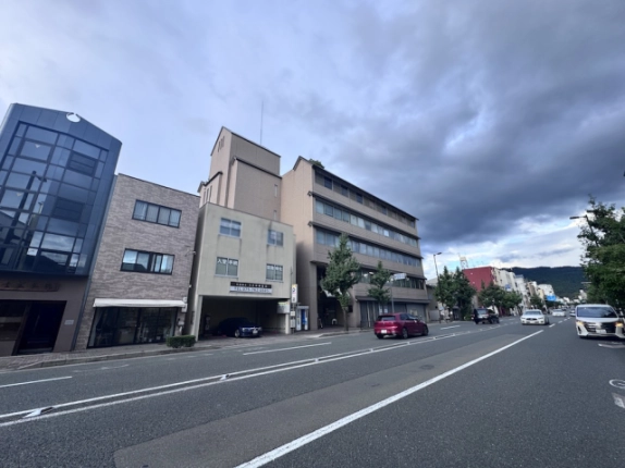 3階に貸店舗事務所がある上田ビルと前面道路。丸太町通沿いの建物と街路樹