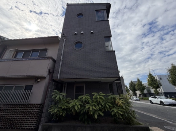 東九条南烏丸テナントの側面。2つの丸窓と建物下部の植栽、右手の前面道路