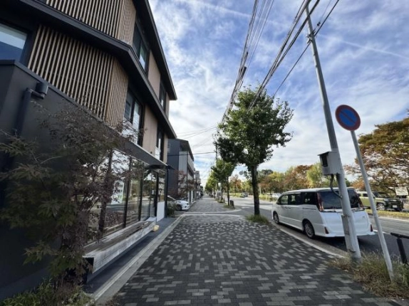 出町柳駅徒歩2分、川端通沿いのブロック舗装の歩道と街路樹。左手にビル1階前の植栽とベンチが続く