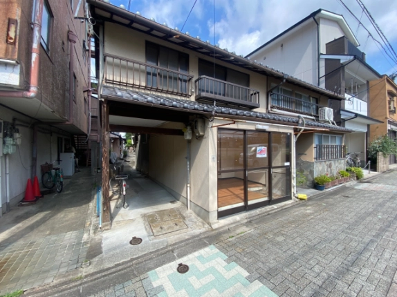 北野白梅町駅近くの一棟貸店舗を斜めから見た外観。軒下の通路と2階の窓
