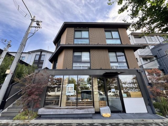 田中下柳町ビルを正面から見た外観。2階・3階に窓と木目調の縦格子が並び、1階はガラス張りの店舗と木のベンチ