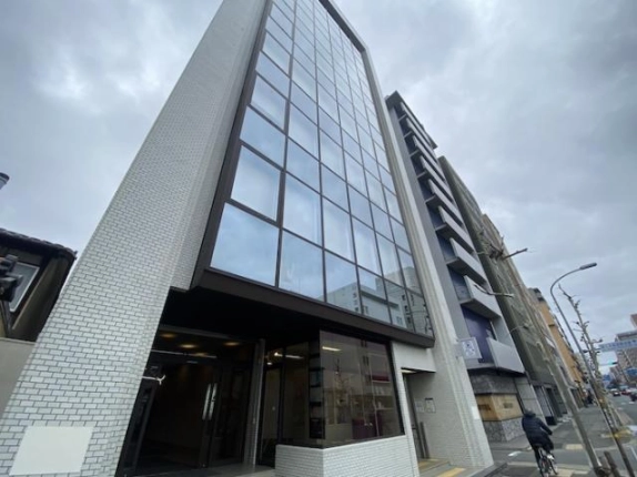 下京区・烏丸通五条下るに建つ8階建ての三善ビル外観。正面はブラウンの枠のガラス張りで、両側を白いタイルの壁が挟む