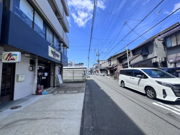 三輝ビルを左手に見た周辺の通り。向かい側に並ぶ住宅と奥へ続く道路