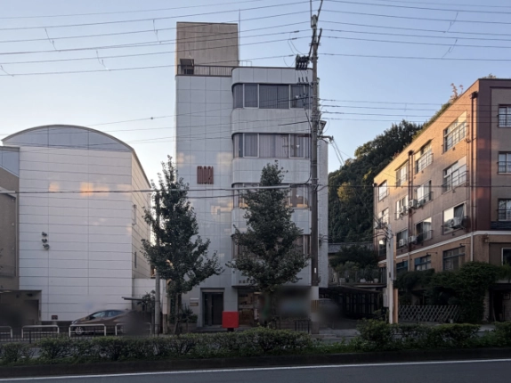 正面から見た白川森ビル。2～5階に丸みのある横長の窓が重なり、左の壁面に「MORI」の文字、1階左にガラス扉の入口がある