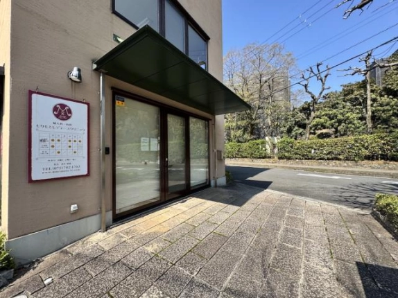 伊佐ビル1階のガラス張りの正面部分。緑色のひさしと入口前の石張りスペース