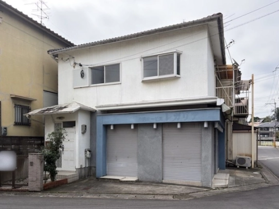 正面から見た樫原蛸田町店舗。青い外枠に並ぶシャッター2枚と左側の白い玄関ドア、2階に窓が2つ