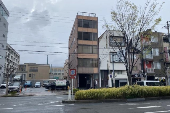 京都市中京区西ノ京東中合町・渡辺ビルの正面外観。茶色の外壁と各階の窓、手前の街路樹