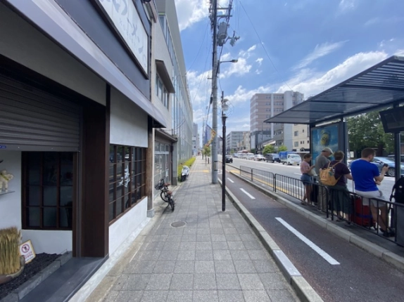 梅小路京都西駅周辺の七条通沿いの様子。店舗前へ続く歩道と道路側のバス停