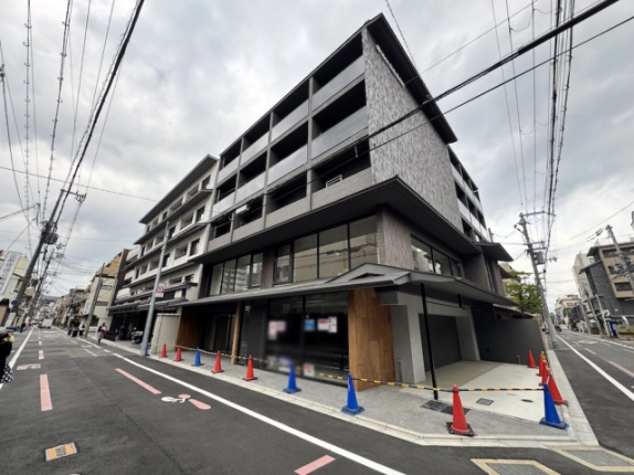 押小路通と富小路通の角に立つ建物全景。上階のバルコニーと下階に広がるガラス面