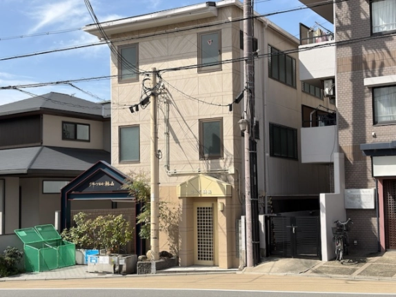 京都市伏見区桃山町鍋島・コーポ鍋島の正面外観。淡いクリーム色の外壁と縦に並ぶ窓