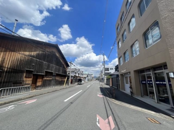 ビルを右手に見た周辺道路。向かい側の木造建物と奥へ続く通り