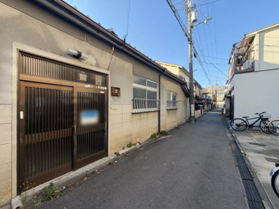 朱雀宝蔵町一棟の外観。茶色の格子戸の玄関と面格子付きの窓が並び、建物沿いに細い路地が奥へ延びる