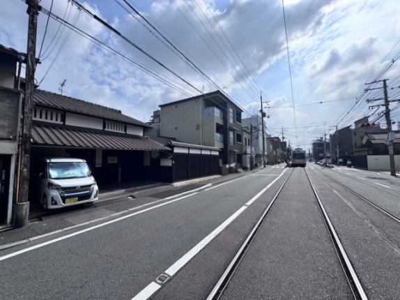 山ノ内宮前町京町家を左手に見た三条通。道路中央から奥へ延びる嵐電の線路