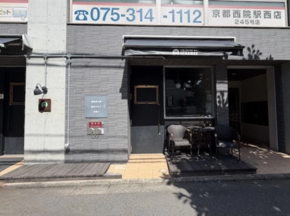 グランドーリア西院の店舗右側。黒い扉と窓、ひさしの下のテーブルと椅子