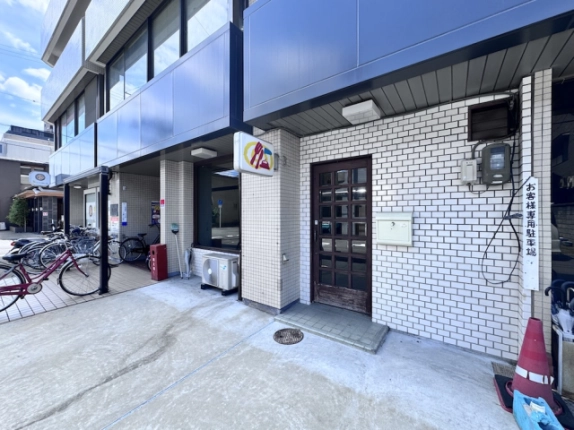 京都市下京区・三輝ビル1階の店舗入口。白いタイル壁と格子状のガラス入り扉